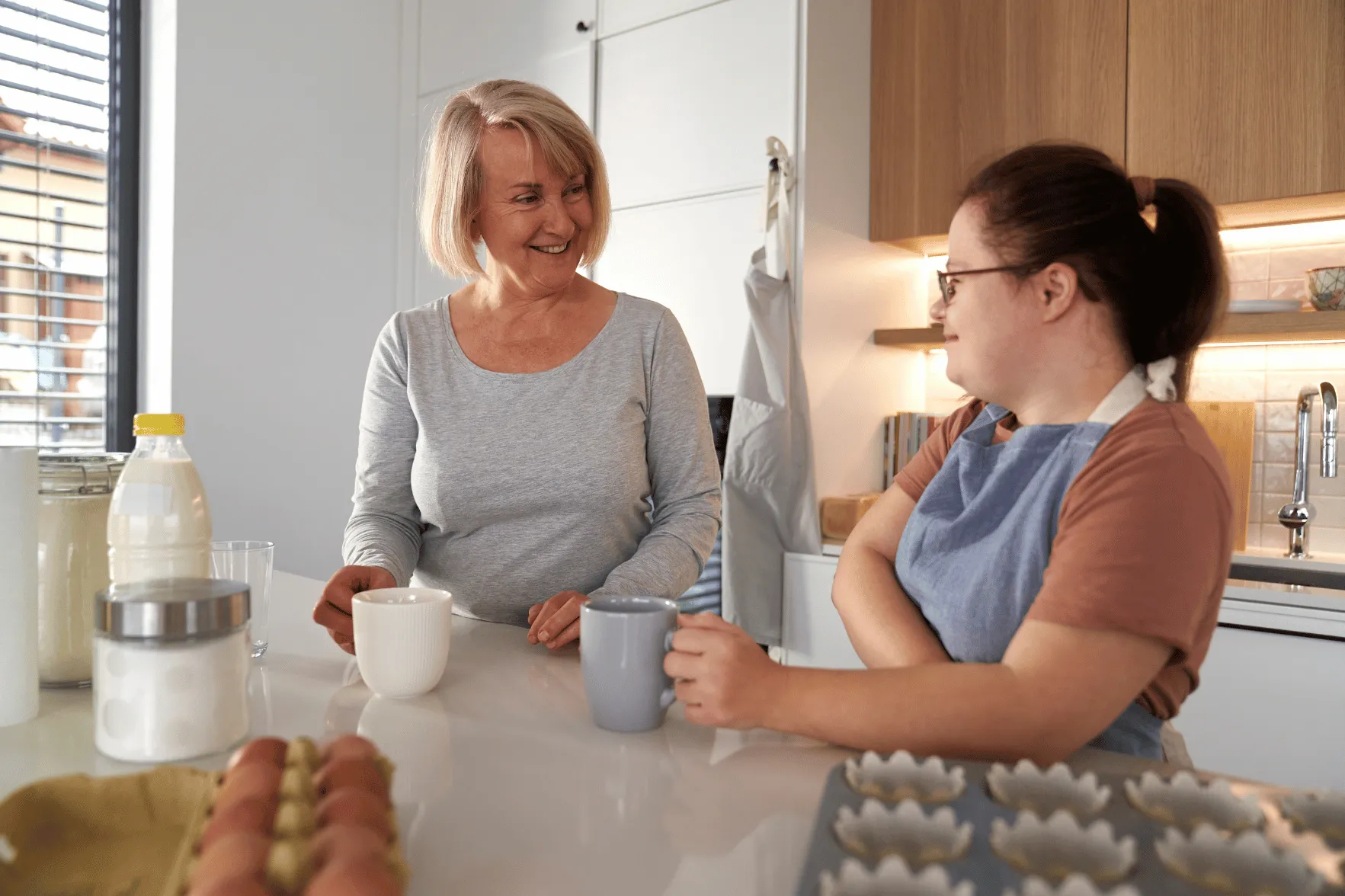 Support worker chatting with disabled woman in kitchen